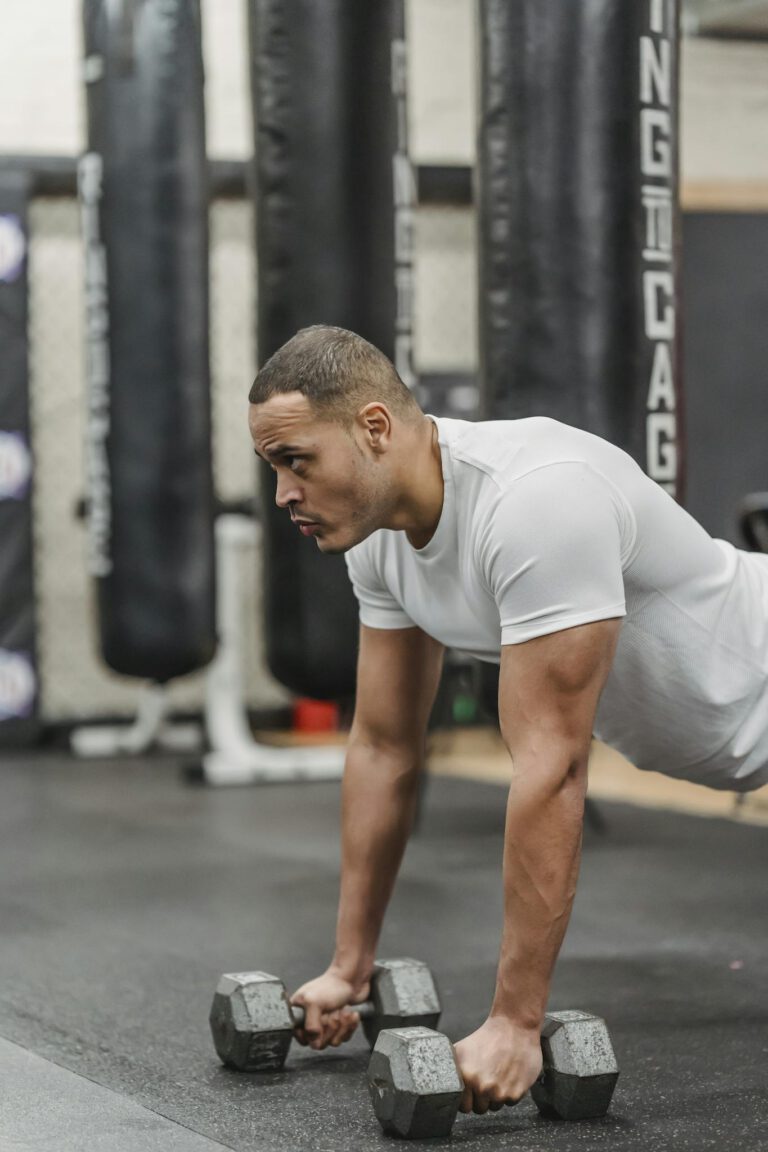 Focused man exercising in a gym with dumbbells, showcasing strength and determination.
